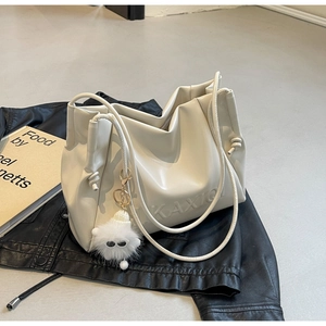 Detail of cream white leather tote bag with drawstring texture and fluffy monster charm