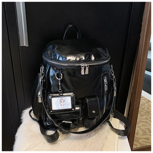Close-up of glossy black PU leather backpack featuring dual zippers and cartoon card holder
