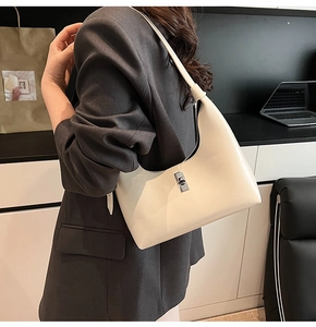 Detail of cream glossy patent leather hobo bag with silver clasp on shoulder