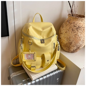 Detail of a bright yellow multi-pocket backpack with a transparent card holder charm