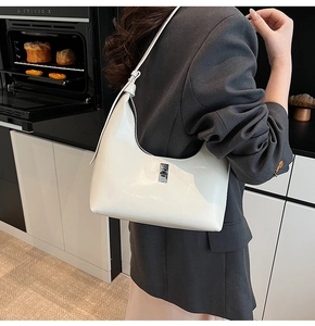 Detail of white glossy patent leather hobo bag with a sleek silver metal buckle strap