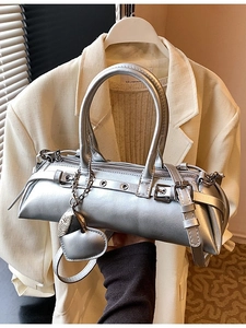 Bolso cilíndrico plateado con acabado metálico y accesorio decorativo de corazón