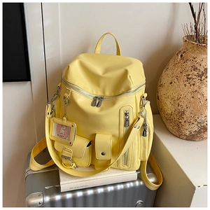 Detail of yellow multi-pocket backpack with waterproof fabric and cat card holder charm