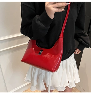 Detail of red crescent hobo bag with silver buckle worn by a model in casual style