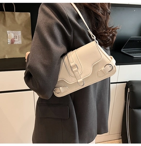 Détail du sac sous l'aisselle beige crème avec boucle décorative porté par le modèle