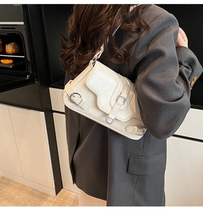 Détail du sac crème avec boucles métalliques et rabat ondulé sur blazer gris foncé