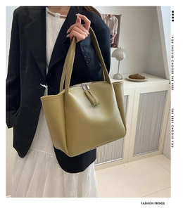 Detail of olive green leather tote bag featuring metal double zippers and pleated side design