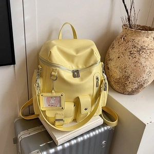 Minimalist light yellow backpack on a suitcase with decorative cat charm and multi-pockets