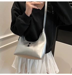 Silver glossy hobo bag with metal buckle shown on model with black sweatshirt and white skirt