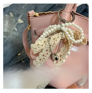 Detail einer glänzenden rosa Tasche mit Perlen-Schleifen-Anhänger und Herz-Anhänger