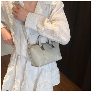 Chic beige crossbody bag with top handles shown on model for size and style