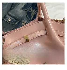 Makroaufnahme der glänzenden rosa Ledertasche mit Goldschnalle und Perlenanhänger