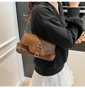 Détail d'un sac porté épaule vintage en cuir PU brillant marron avec boucles argentées