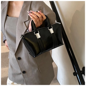 Polished black leather handbag styled with grey blazer and silver metal hardware details
