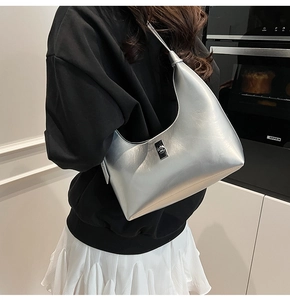 Detail of silver metallic hobo bag featuring a sleek rectangular metal turn-lock closure