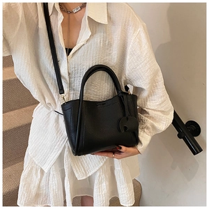 Detail of black lychee grain tote bag with detachable strap and tonal decorative tag