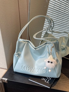 Light blue faux leather shoulder bag with pleated design and white plush charm on display