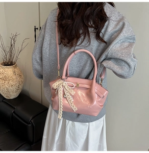 Detail der rosa Lacklederhandtasche mit Spitzenschleife und Perlenkette am Model