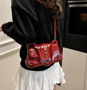 Detail of dark red glossy leather shoulder bag with silver buckle on black hoodie