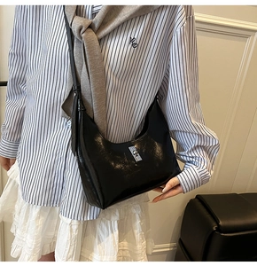 Detail of glossy black hobo bag showing silver metal lock and shiny leather texture