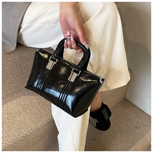 Detail of a chic black glossy leather handbag with silver hardware and top handle