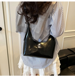 Close-up of a glossy black crescent shoulder bag with a sleek silver metallic buckle