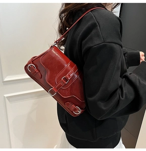 Détail d'un sac d'épaule en similicuir rouge brillant avec boucles métalliques