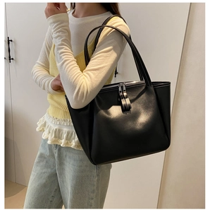 Black leather tote bag with contrast stitching shown on a model for size perspective