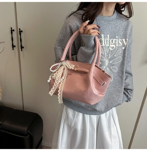 Detail der rosa Kunstleder-Handtasche mit Spitzenschleife und Perlenanhänger am Griff