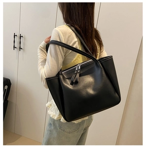 Detail of contrast white stitching and dual zipper on black leather tote bag for women