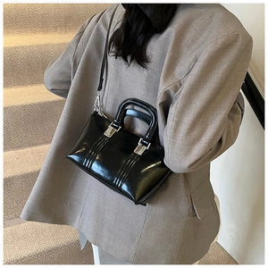 Detail of glossy black patent leather handbag with silver metal hardware and sturdy handle