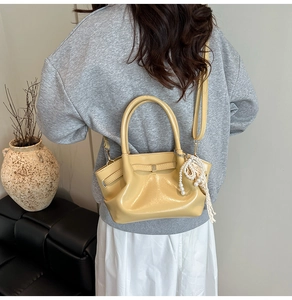 Detail der hellgelben glänzenden Tasche mit Perlenanhänger im Lifestyle-Look