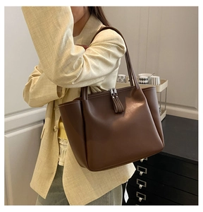 Detail of dark brown tote bag featuring contrast white stitching and top zipper closure