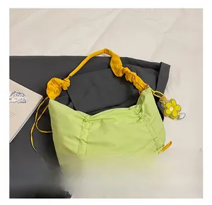 Détail du sac plissé vert avec bandoulière nuage jaune et breloque fleurie élégante