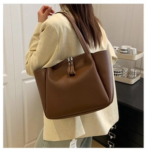 Detail of soft brown leather tote bag with white contrast stitching and dual zippers
