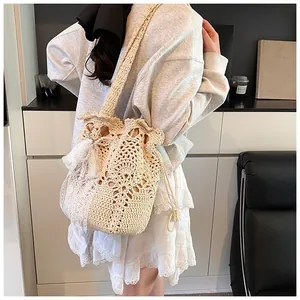 Detail view of a beige woven bucket bag with floral patterns and lace tassels