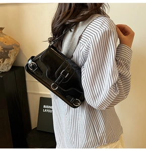 Vue détaillée d'un sac d'épaule en cuir verni noir avec boucle en métal argenté et sangle
