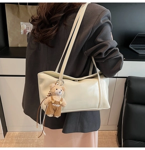 Detail of cream shoulder bag in matte PU leather with a cute teddy bear plush charm