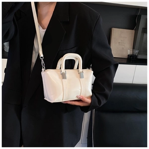 Chic cream white crossbody bag with glossy finish shown on model in black blazer