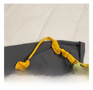 Détail du sac bandoulière vert clair avec poignée plissée jaune et breloque fleur