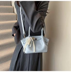 Nahaufnahme hellblaue Faltenhandtasche mit Perlen- und Spitzenbogenanhänger an Model