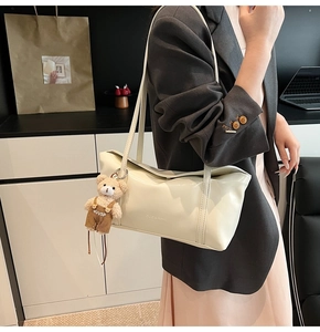 Detailed view of cream white faux leather shoulder bag with cute bear charm detail