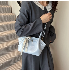 Detailansicht hellblaue Handtasche mit Perlen-Schleife und Spitze in schicker Optik