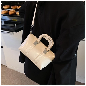 Detailed view of an off-white glossy Boston bag styled with a chic black blazer outfit