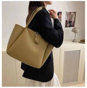 Detail of a large olive leather tote bag styled with a professional black blazer outfit