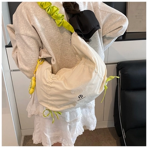 Détail du sac croissant en toile avec bandoulière plissée verte et pendentif smiley jaune
