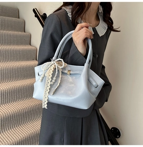 Detail der hellblauen Handtasche aus Kunstleder mit Spitzenschleife und Perlenanhänger