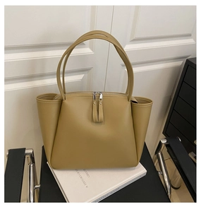 Detail of khaki leather tote bag showing white contrast stitching and dual metal zippers
