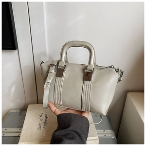 Detail of grey leather Boston bag with silver hardware held against a book background