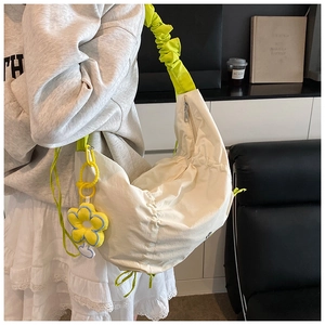 Détail du sac beige en nylon avec bandoulière à volants vert vif et breloque tournesol